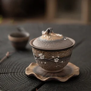 Full view of hand-carved plum blossom ceramic gaiwan tea set with lotus saucer
