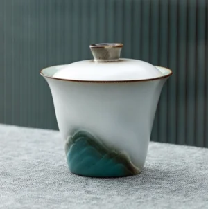 Hand-painted mountain motif ceramic gaiwan lidded tea bowl on natural wood background
