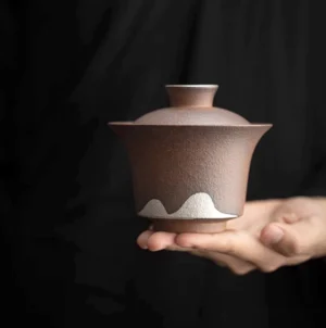 Full side view of handmade rough clay gaiwan with white mountain pattern