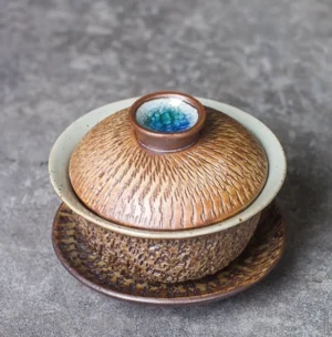 Mini hand-carved ceramic gaiwan with earthy brown bark texture glaze and blue-green kiln change lid knob