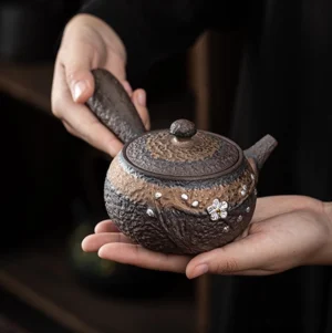 Handcrafted ceramic side handle teapot with rustic bark texture and silver floral decor main view